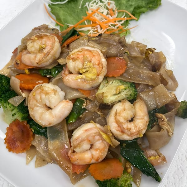 Thai Pad See Ew with shrimp, broccoli, and carrots on a white plate.