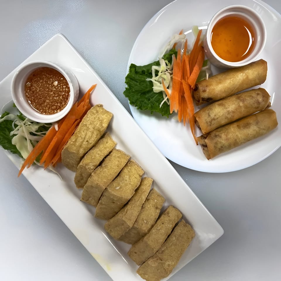 Plates of golden fried tofu sticks with peanut sauce and crispy spring rolls with sweet chili sauce.