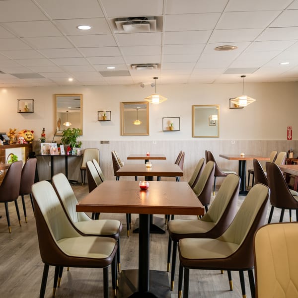 An empty dining room at Bangkok Chinatown Cuisine with wooden tables, modern chairs, and decorative mirrors.