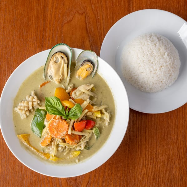 Thai green curry with mussels, squid, vegetables, and basil, served with white rice.
