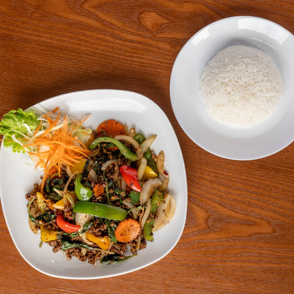 Thai basil stir-fry with ground meat and vegetables, served with a side of white rice.