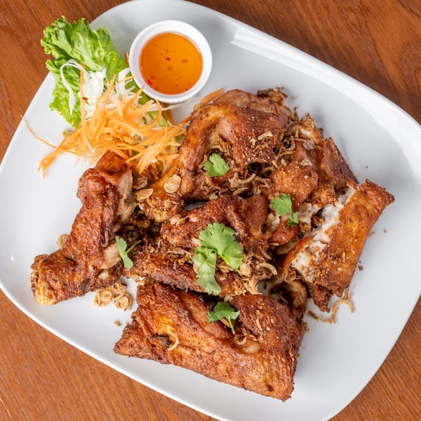 Crispy fried chicken pieces with garlic, cilantro, shredded carrots, lettuce, and sweet chili sauce.
