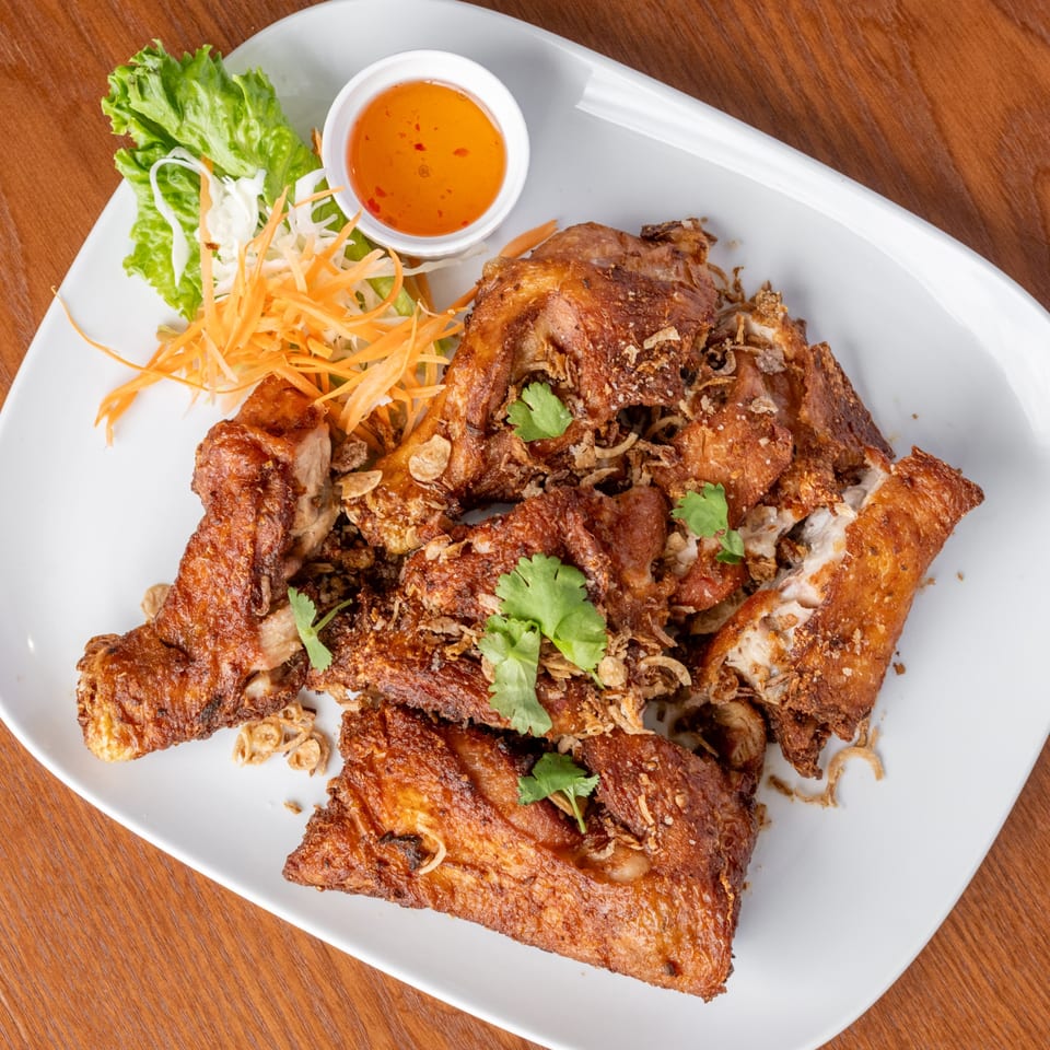 Crispy fried chicken pieces with garlic, cilantro, shredded carrots, lettuce, and sweet chili sauce.