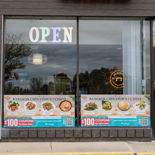 The exterior of Bangkok Chinatown Cuisine, featuring an "OPEN" sign and promotional banners with Thai dishes.